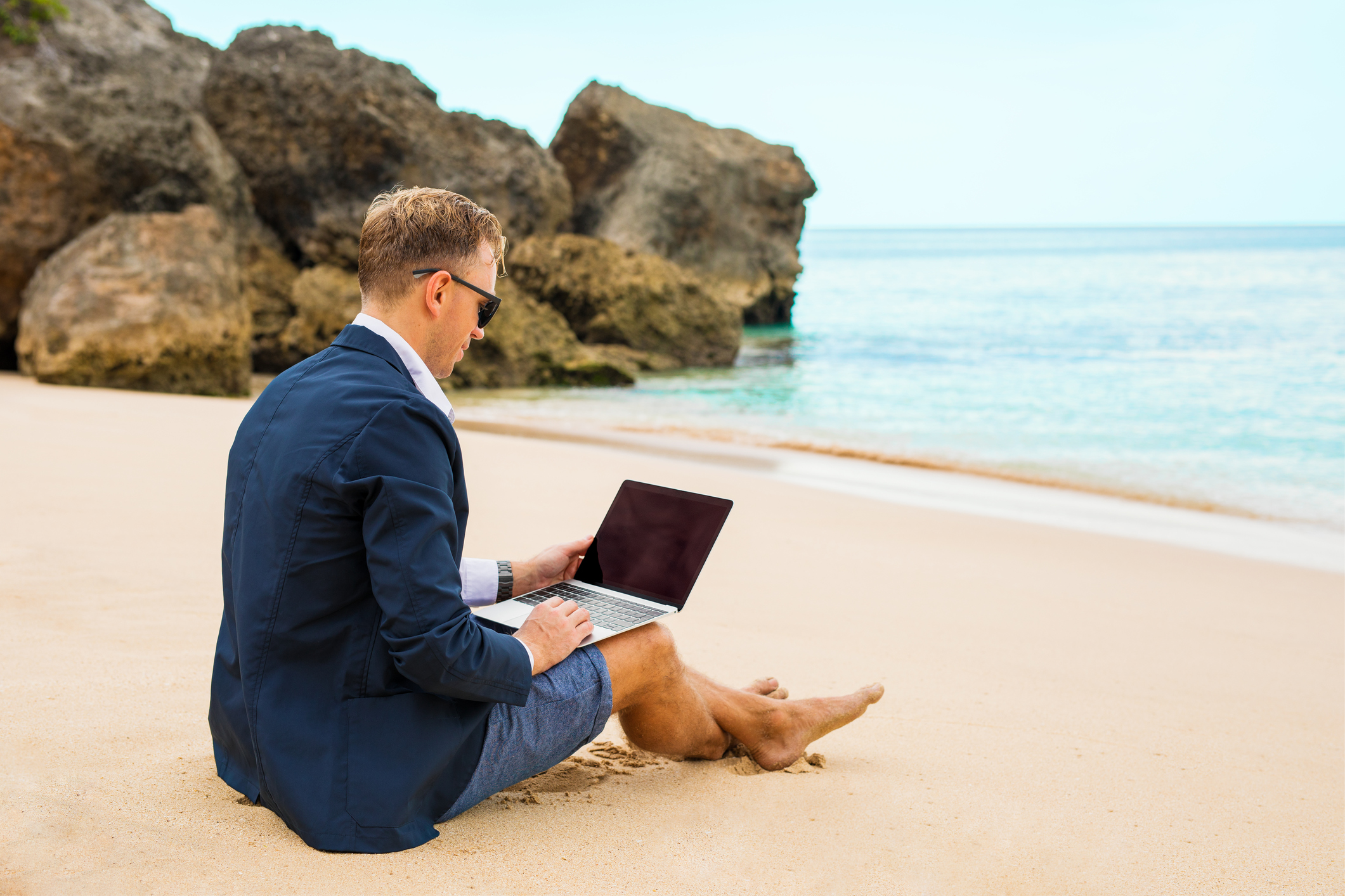 Businessman working with laptop on the beach