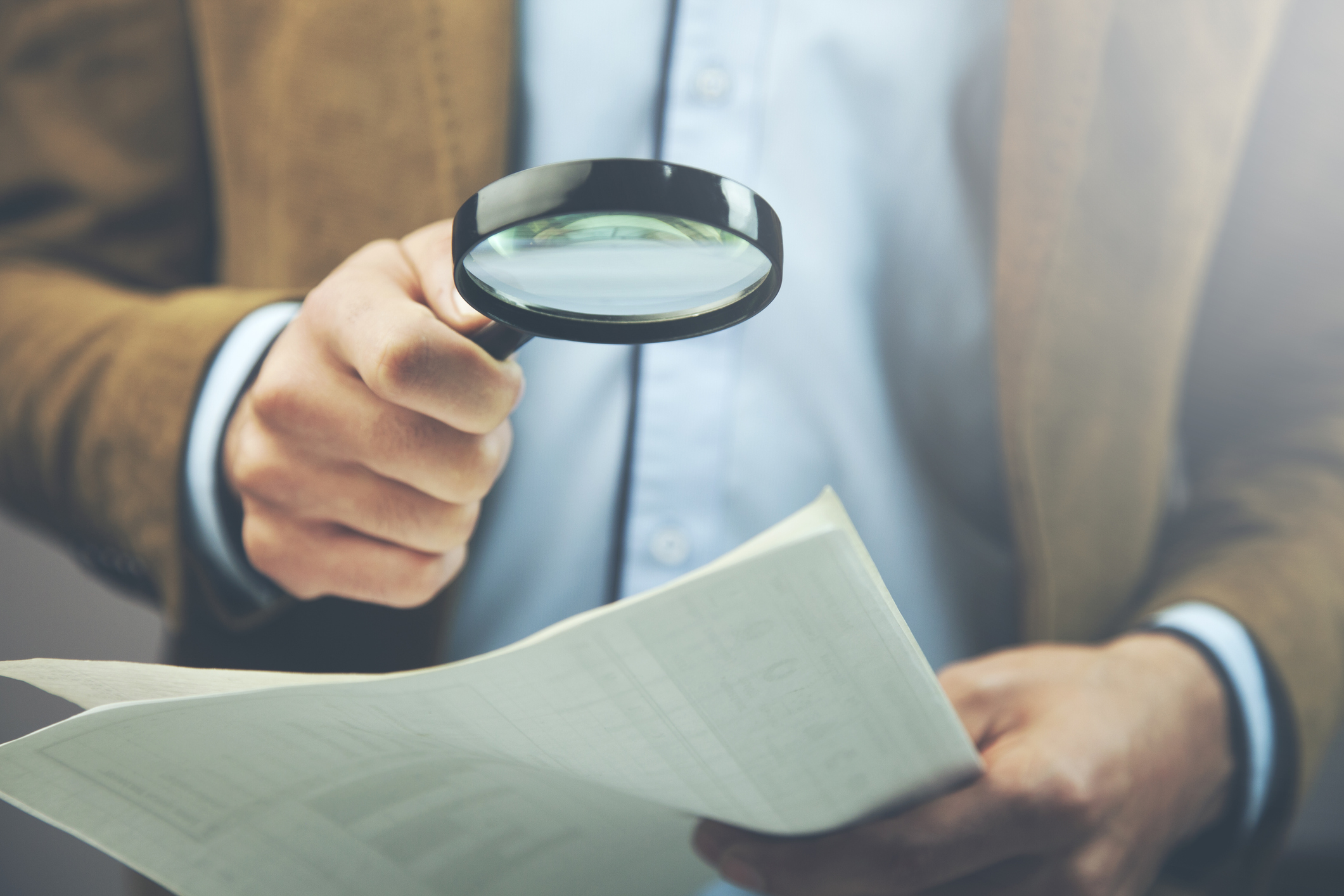 Businessman hand document and magnifier in office