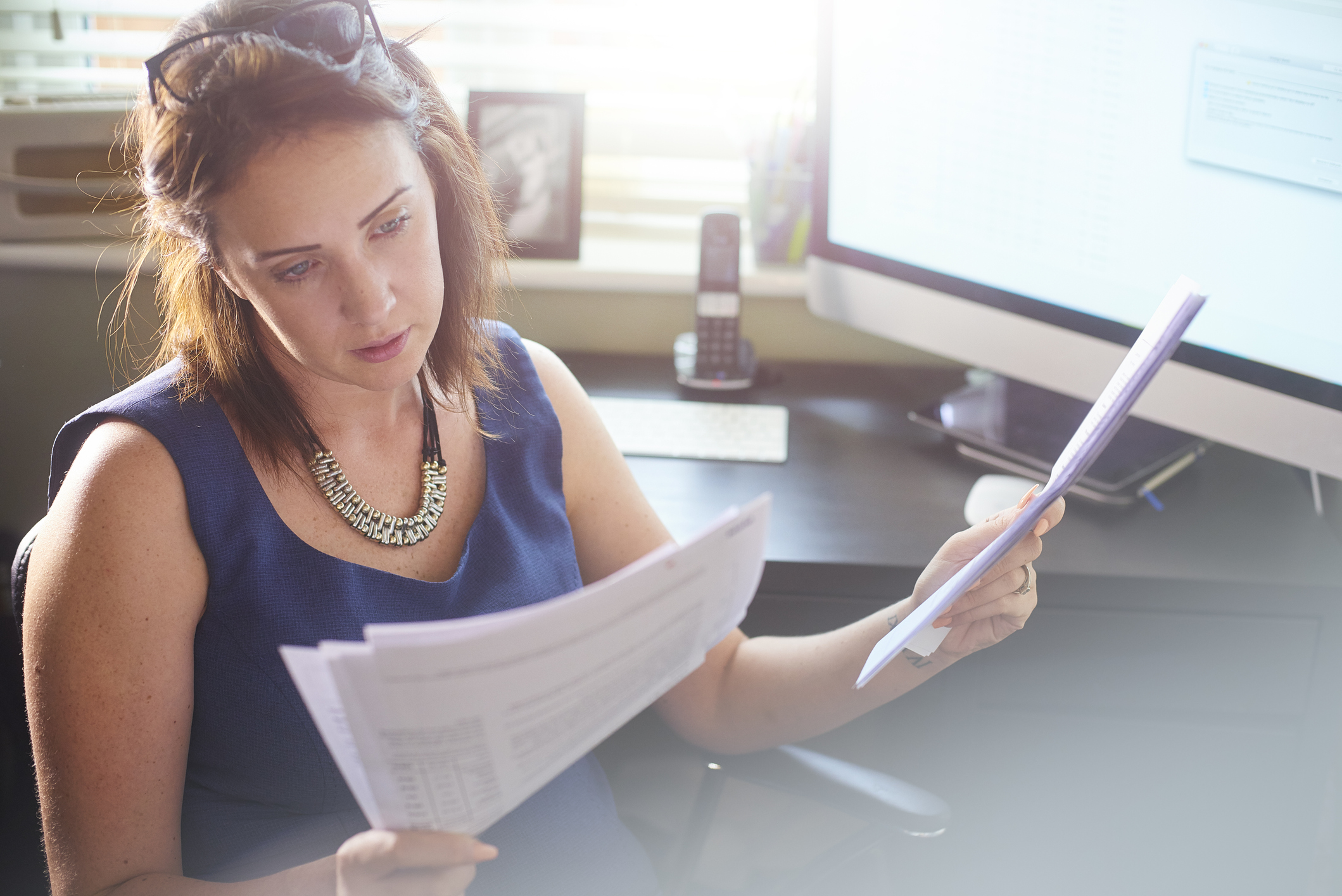 woman sits at her desk reading through paperwork